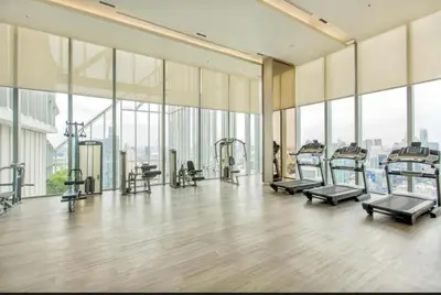 a gym with treadmills and machines in a building with windows at Hyde Sukhumvit 11 Bankok in Bangkok