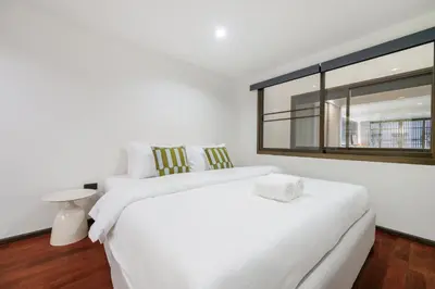a white bedroom with two beds and a window at 4BR House For Family&Friends in Bangkok