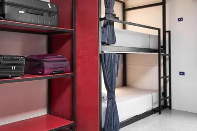 a room with two bunk beds and a red wall at Kinboshi Hostel Silom in Bangkok