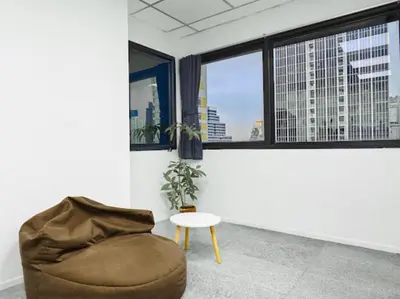 a room with a couch and a table and windows at Kinboshi Hostel Silom in Bangkok