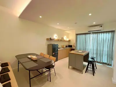 a living room with a table and a kitchen at Slaap36 5BR Home with Parking, Walk to BTS Ari in Bangkok