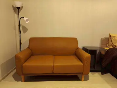 a brown leather couch in a living room with a lamp at Condo Studio Sukhumvit 115 BTS Pu Chao in Ban Khlong Samrong