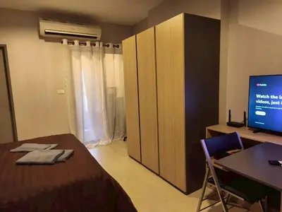 a bedroom with a bed and a desk and a tv at Condo Studio Sukhumvit 115 BTS Pu Chao in Ban Khlong Samrong