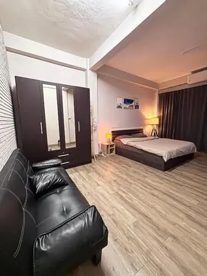 a hotel room with a bed and a leather couch at Mango Rooms & Rooftop in Bangkok
