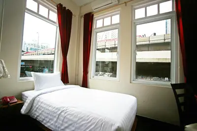 a bedroom with a white bed and two windows at The Myth - Sud Sathorn in Bangkok