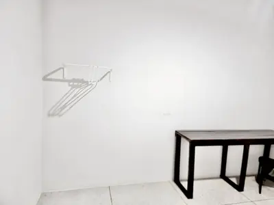a glass table and a wooden table against a white wall at Mitr Inn Khaosan Road - มิตรอินน์ ถนน ข้าวสาร in Bangkok