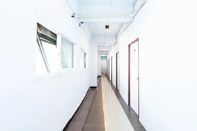 an empty hallway with white walls and windows at XX The Hidden Khaosan Rambutri - เดอะ ฮิดเดน ข้าวสาร รามบุตรี xPro in Bangkok