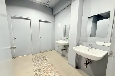 a white bathroom with two sinks and a shower at Sukhum Huai Khwang Guest House in Bangkok
