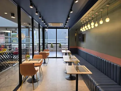 a restaurant with tables and chairs and windows at ARNI HER Ladies Hotel - Female Only in Bangkok