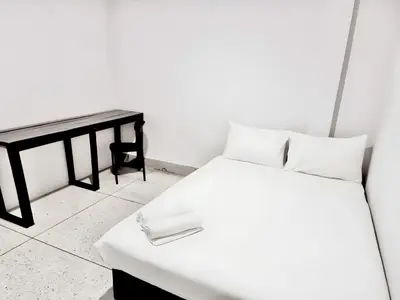 a bedroom with a white bed and a table at XX Mitr Inn Khaosan Road - มิตร อินน์ ถนนข้าวสาร in Bangkok