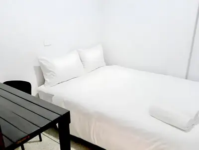 a bedroom with two white beds and a table at XX Mitr Inn Khaosan Road - มิตร อินน์ ถนนข้าวสาร in Bangkok