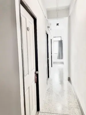 an empty hallway with white walls and a white door at XX Mitr Inn Khaosan Road - มิตร อินน์ ถนนข้าวสาร in Bangkok