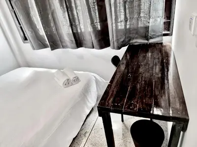 a small room with a bed and a wooden table at XX Mitr Inn Khaosan Road - มิตร อินน์ ถนนข้าวสาร in Bangkok