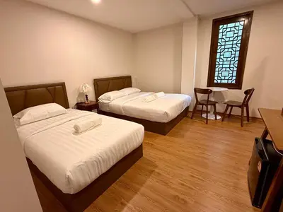 a room with two beds and a table and a window at Soultel โซลเทล in Khlong San