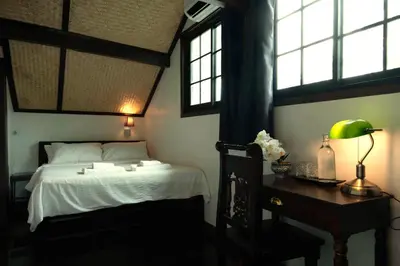 a bedroom with a bed and a desk and windows at Casa Acero in Bangkok