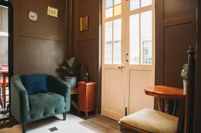 a living room with a green chair and a door at Casa Acero in Bangkok