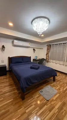 a bedroom with a large bed and a chandelier at Rewadee House in Nonthaburi