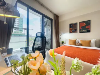 a bedroom with a bed and a desk with a laptop at Walk to BTS Ekkamai l Urban Sukhumvit Living l Fast WiFi in Bangkok
