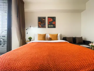 a bedroom with a large orange bed with an orange blanket at Walk to BTS Ekkamai l Urban Sukhumvit Living l Fast WiFi in Bangkok