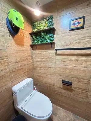 a bathroom with a toilet with a helmet on the wall at Secret Retro Vintage Building ห้องลับเรโทรในตึกวินเทจ in Ban Song Hong