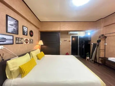 a bedroom with a large white bed with yellow pillows at Secret Retro Vintage Building ห้องลับเรโทรในตึกวินเทจ in Ban Song Hong