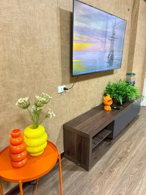 a living room with a television and a table with a vase at Secret Retro Vintage Building ห้องลับเรโทรในตึกวินเทจ in Ban Song Hong