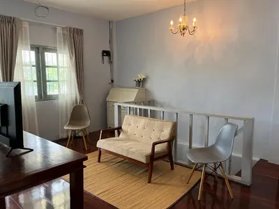 a living room with a chair and a piano at Saen Saran property in Sathani Bang Ramat
