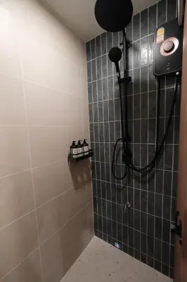 a shower with a shower head in a bathroom at The Shantipan Jasmine - Cozy City Retreat 400m from BTS Station in Bangkok