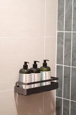 a shelf in a bathroom with three bottles of soap at The Shantipan Jasmine - Cozy City Retreat 400m from BTS Station in Bangkok