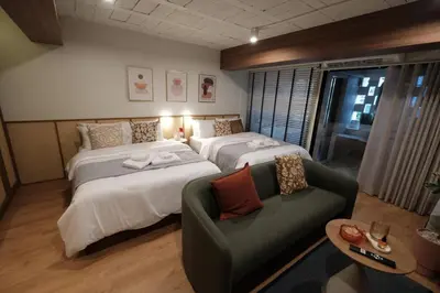 a hotel room with two beds and a couch at The Shantipan Mandala - Cozy City Retreat 400m from BTS Station in Bangkok
