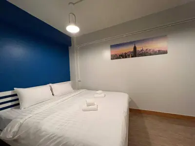 a bedroom with a large white bed with a blue wall at Pratunam Family House 2 in Bangkok