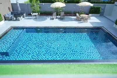 a swimming pool with blue tiles in a yard at Three Seasons Bangkok in Bangkok