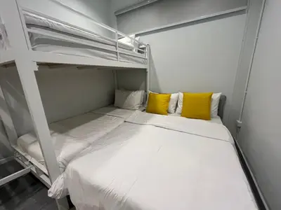 a small bedroom with a bunk bed with yellow pillows at Kanal Bangkok Service Residence in Ban Khlong Bang Chak