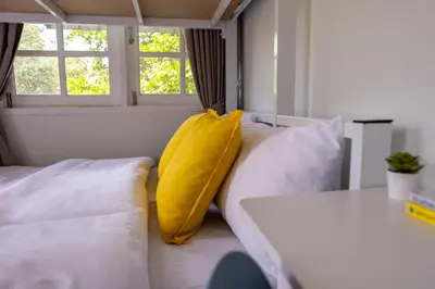 a room with two beds and a yellow pillow at Kanal Bangkok Service Residence in Ban Khlong Bang Chak