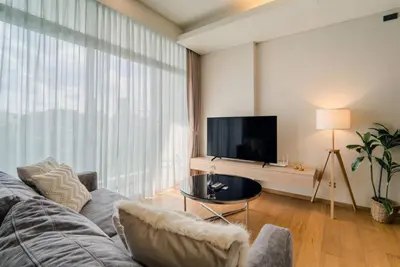 a living room with a couch and a flat screen tv at Panoramic 2BR Ekkamai with infinity pool in Bangkok
