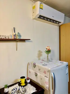 a kitchen with a washing machine with a table with flowers on it at Ally home 12 23 in Thung Si Kan