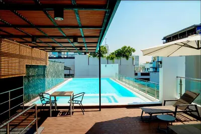 a pool on the roof of a building with chairs and an umbrella at 6th Avenue Sukhumvit BKK Two Bedrooms BTS Asok Nana MRT Sukhumvit in Bangkok