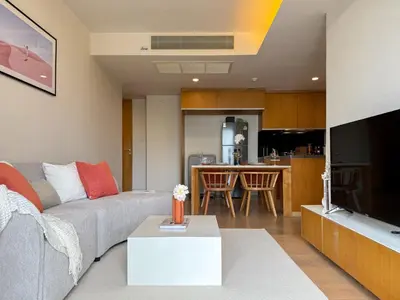 a living room with a grey couch and a kitchen at Expansive Luxury 2BR - Ultra Fast Wifi - Phrom Phong in Bangkok