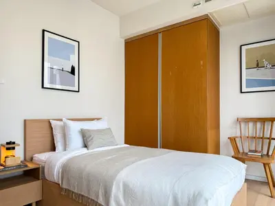 a bedroom with a large bed and a wooden cabinet at Expansive Luxury 2BR - Ultra Fast Wifi - Phrom Phong in Bangkok
