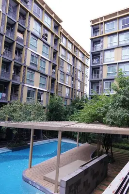 a large apartment building with a bench in front of a pool at Metroluxe rama4 , city center in Bangkok