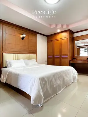 a bedroom with a large white bed with wooden cabinets at Prestige in Bangna