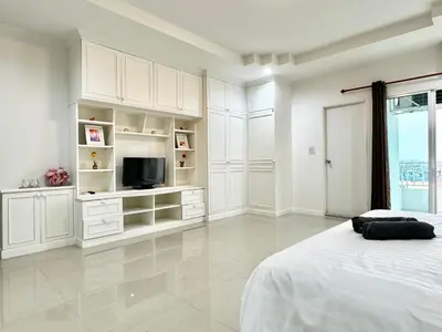 a white room with a bed and a television at Prestige in Bangna