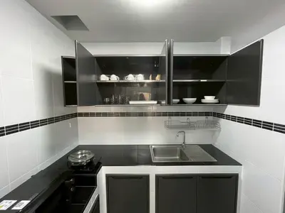 a kitchen with black cabinets and a sink at Ananta House in Bang Su