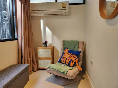 a room with a chair with a pillow on it at Be Cozy Silom Modern 2BR 1-min to BTS & MRT in Bangkok