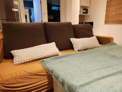 a brown couch with two pillows on top of it at Be Cozy Silom Modern 2BR 1-min to BTS & MRT in Bangkok