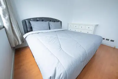 a bed with a white blanket and a black chair at 2Bed Room Condo Near iConsiam & BTS Krungthonburi in Bangkok