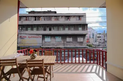 a balcony with a table and chairs and a building at The Open House Cafe and Hostel in Bangkok