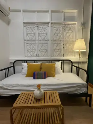 a bed with yellow pillows and a table in a room at The Open House Cafe and Hostel in Bangkok