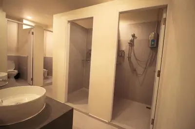 a bathroom with a white sink and a shower at The Open House Cafe and Hostel in Bangkok