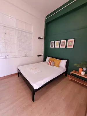 a bedroom with a large bed with a green wall at The Open House Cafe and Hostel in Bangkok